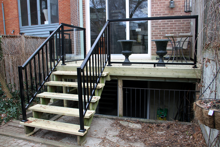 Backyard patio wood deck with glass and metal railing built in Cabbagetown, Toronto.